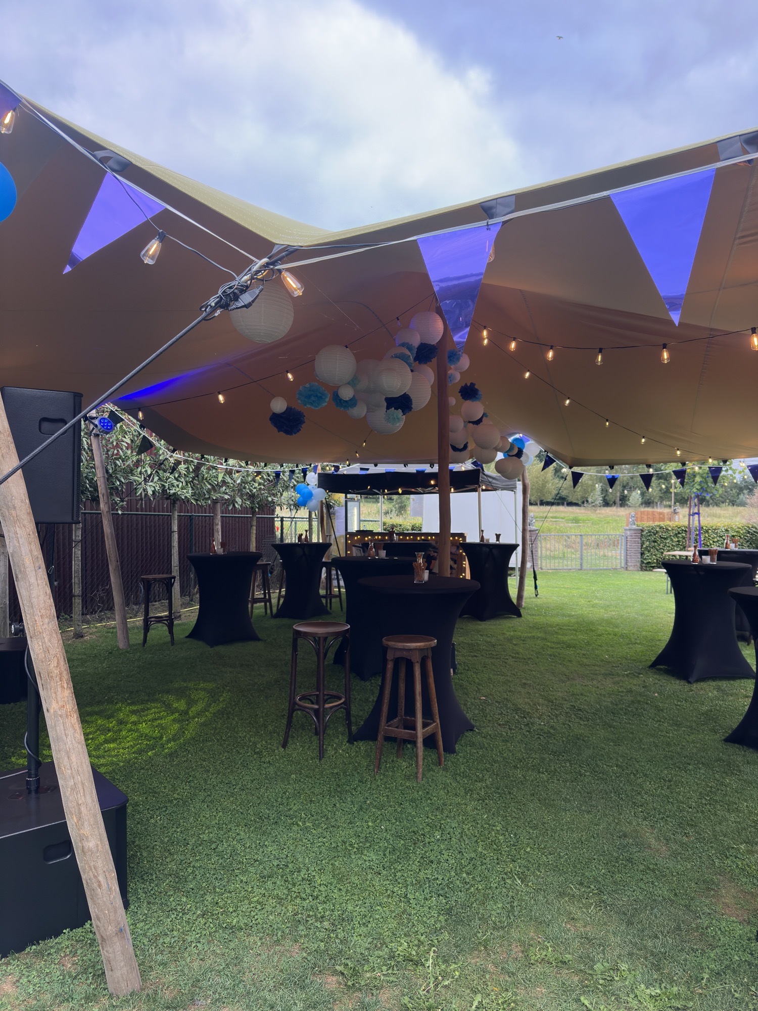 Feestopstelling onder de stretchtent met statafels en sfeerverlichting