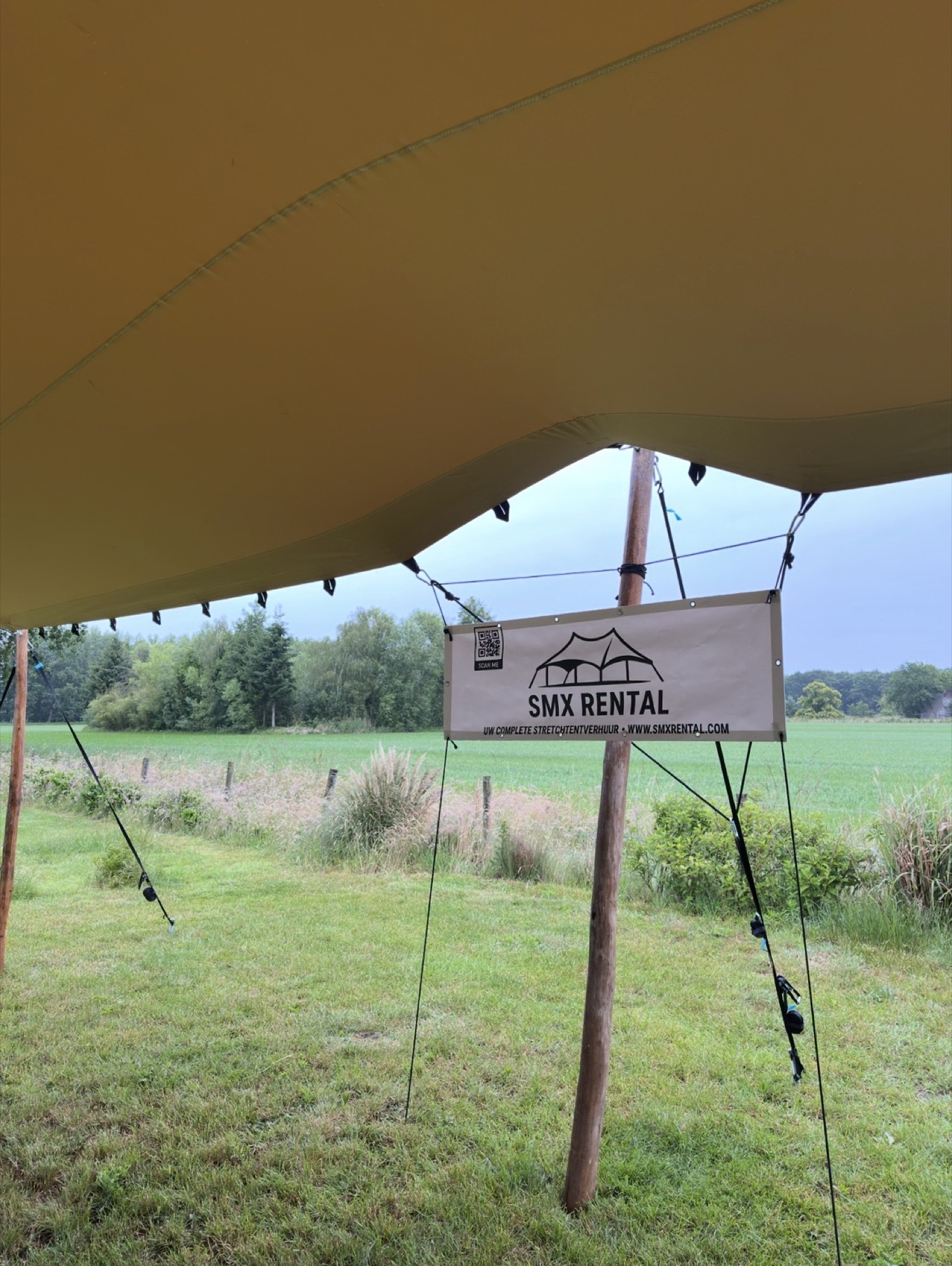 Onder de stretchtent met het SMX Rental-bord en uitzicht op het veld