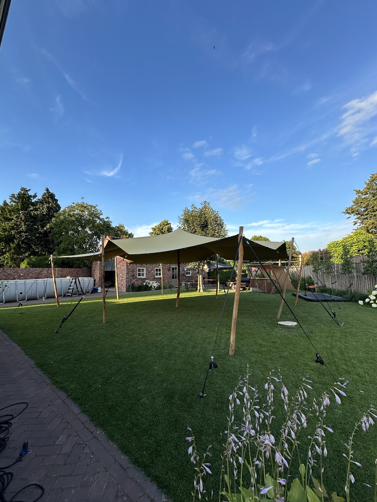 Stretchtent van SMX Rental opgesteld in een tuin tijdens het gouden uur