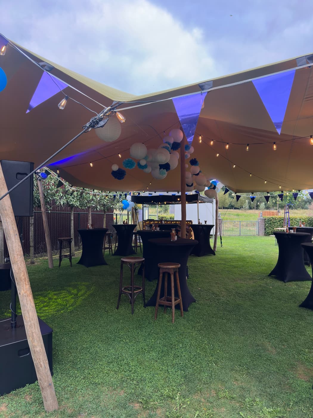 Feestopstelling onder de stretchtent met statafels en sfeerverlichting